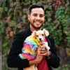 Man holding dog a dog dressed in rainbow colors